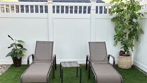 A patio with two lounge chairs, a small table, and potted plants. - Cape May Home in Newest Hot Spot: Centrally Located, Family Friendly, Sleeps 12! (Cape May)
