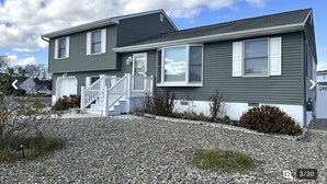 A two-story house with a front porch, a garage, and a gravel driveway. - Cape May Home in Newest Hot Spot: Centrally Located, Family Friendly, Sleeps 12! (Cape May)