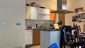 Una cocina compacta con armarios blancos, una isla central y una estufa empotrada.