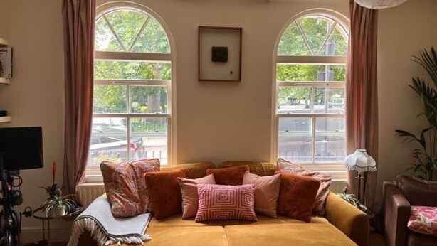 Una habitación acogedora con un conjunto de sofás, ventanas amplias y un cuadro en la pared.