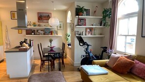 Un espacio habitable compacto con kitchenette, zona de comedor y sofá con cojines.