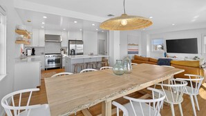 Una cocina moderna con armarios blancos, una mesa de comedor de madera y sillas blancas.
