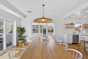 Una cocina moderna con armarios blancos, una mesa de comedor de madera y un ventanal grande.