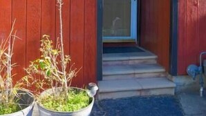 A red building with a door labeled "801" and a small set of steps leading up to it. There are two metal buckets with plants on the ground in front of the building. - Relaxing Home With SF Bay View

 (Millbrae)