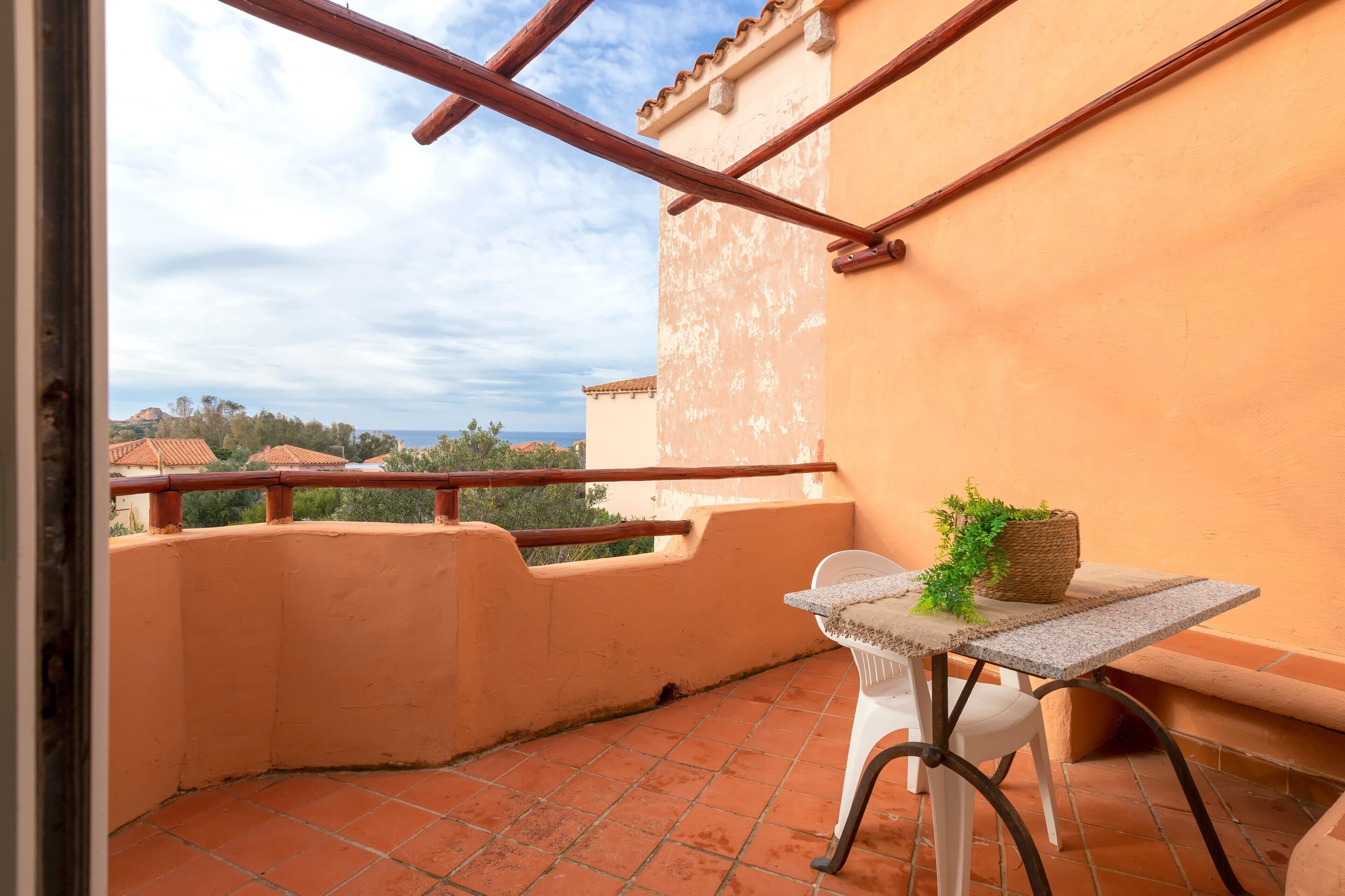 Ein Balkon mit Tisch, Stuhl und Blumentopf.