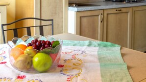 Een keuken met een fruitschaal op een tafel, een stoel en een betegelde achterwand.