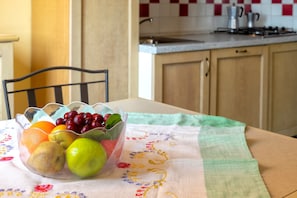 Eine Küche mit Obstschale auf einem Tisch, einem Stuhl und einer gefliesten Spritzschutzwand.