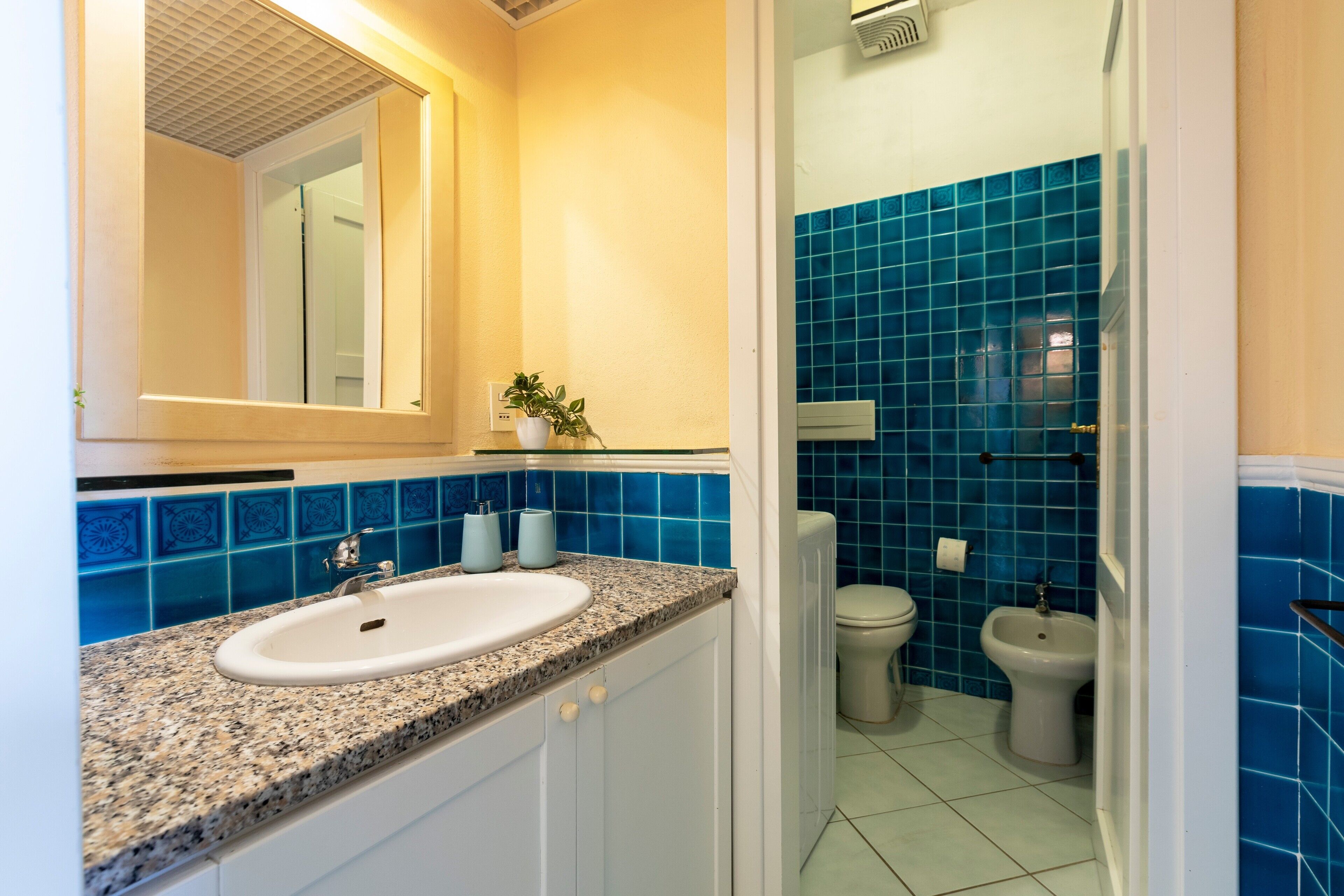 A bathroom with a sink, mirror, and blue-tiled walls.