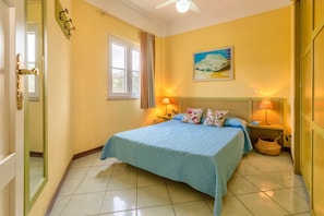 Un dormitorio con una cama, dos lámparas de noche, un cuadro y una ventana con cortinas.