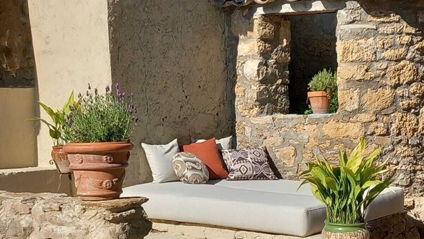 A stone building with a rustic exterior, a small window, and a white outdoor sofa with cushions. - Finca Rural Ideal Familia CON Mascota CON Jardin, Alberca BBQ Y Parking Privado (Sant Romà d'Abella)