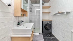 A compact bathroom with a white sink, mirror, and a built-in shower.
