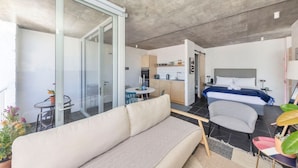 A modern apartment with a living area, kitchenette, and a bedroom.