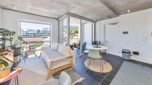 A modern living room with a sofa, chairs, a dining table, and potted plants.