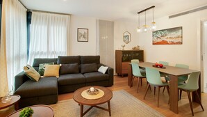 Ein Wohnzimmer mit Sofa, Esstisch, Stühlen und Couchtisch.