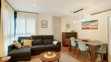 A living room with a sofa, dining table, chairs, and a coffee table.