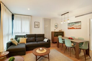 A living room with a sofa, dining table, chairs, and a coffee table.