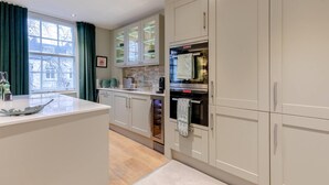 A modern kitchen with white cabinets, a central island, and a built-in oven. - Elegant 1BD Flat in the Heart of Notting Hill! (London)