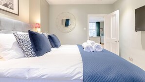 A hotel room with a bed, a round mirror, a TV, and a view of the hallway. - Elegant 1BD Flat in the Heart of Notting Hill! (London)