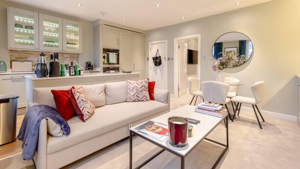 A modern living room with a sofa, coffee table, and chairs. There is a kitchen area with cabinets and a dining table. - Elegant 1BD Flat in the Heart of Notting Hill! (London)