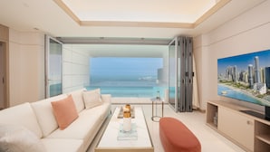 A modern living room with a sofa, coffee table, and TV, featuring a cityscape view through large windows. -  FIVE LUXE (Dubai)