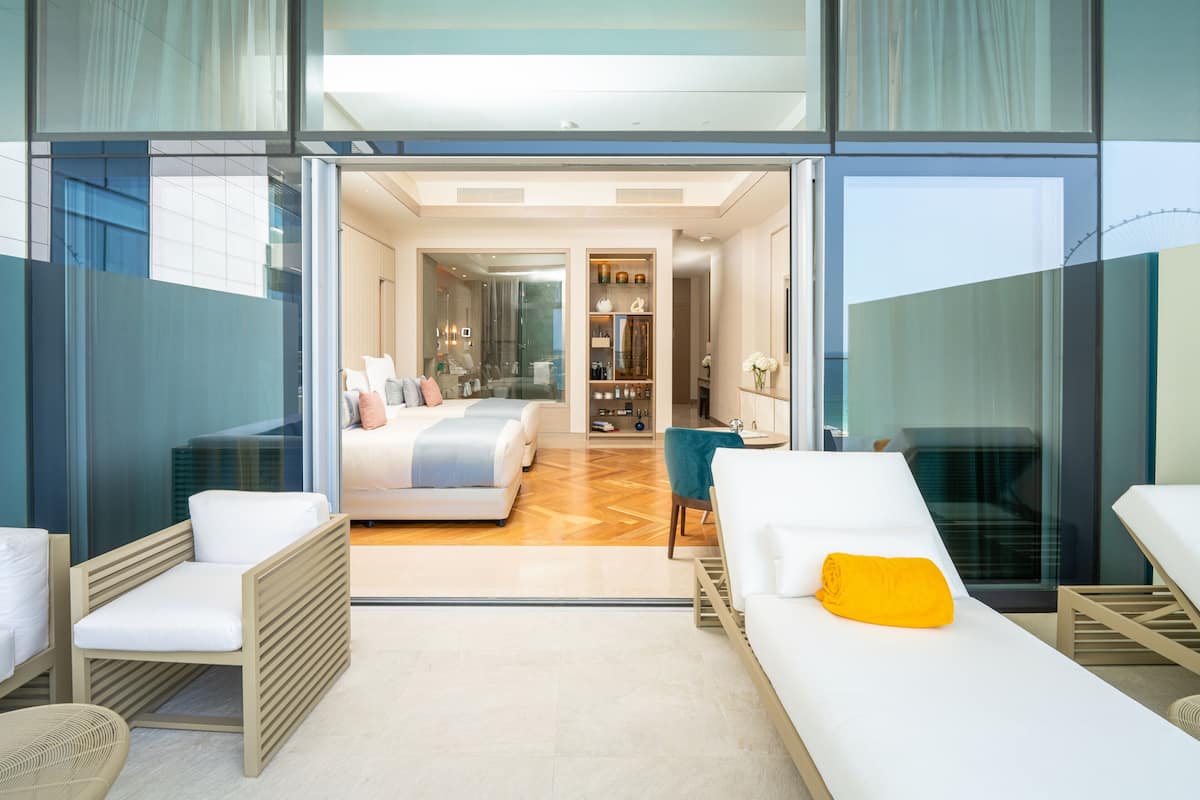 Habitación de hotel moderna con una cama grande, un sofá y un balcón con vistas.