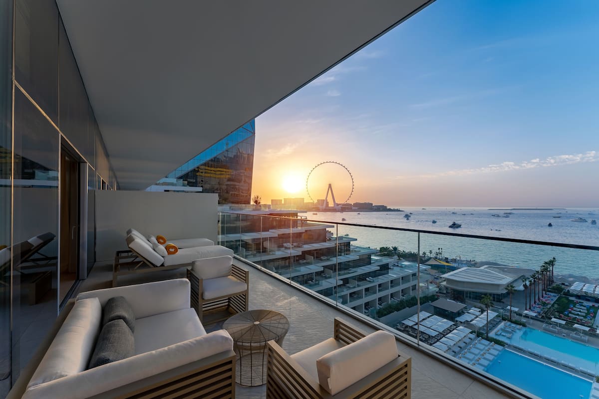 Un balcón moderno con vistas a la puesta de sol, una noria y una zona de piscina.