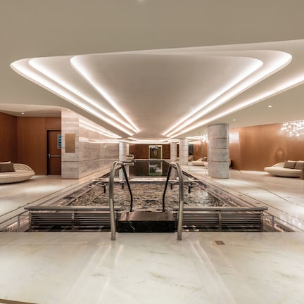 A modern lobby with a central water feature, seating areas, and a distinctive ceiling design.