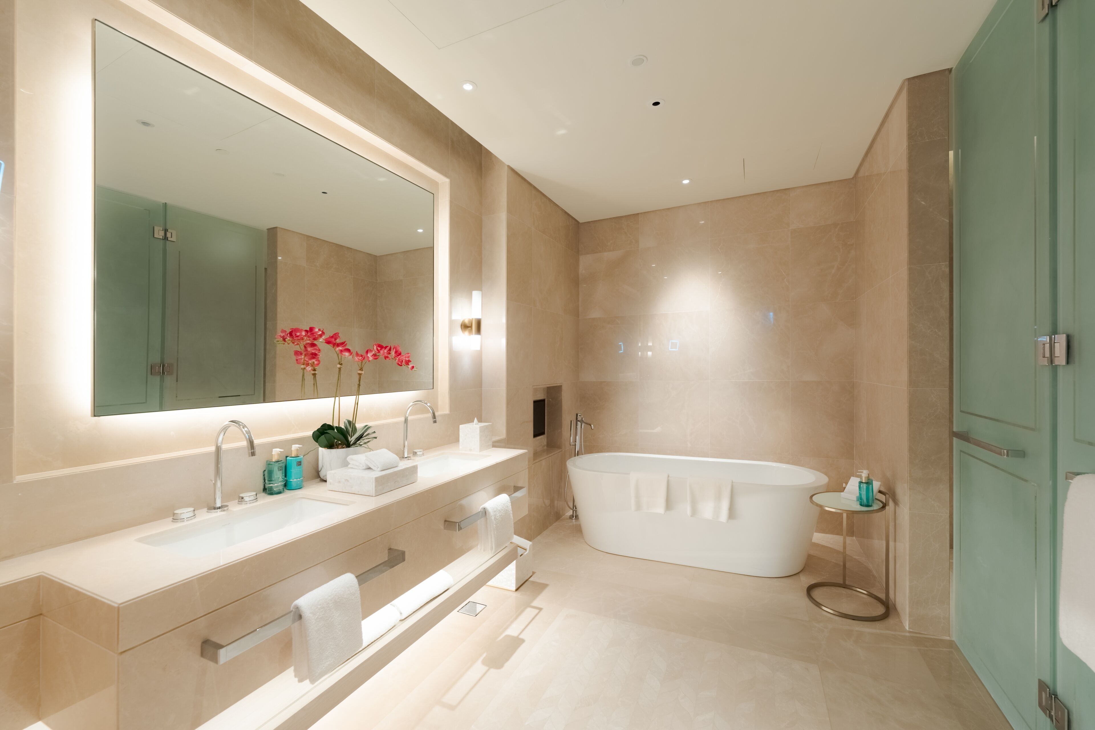A modern bathroom with a large mirror, a freestanding bathtub, and a vanity with a sink and towel rack.