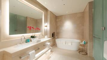A modern bathroom with a large mirror, a freestanding bathtub, and a vanity with a sink and towel rack.