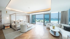 A modern bedroom with a large bed, a sofa, a coffee table, and a view of the ocean. -  FIVE LUXE (Dubai)