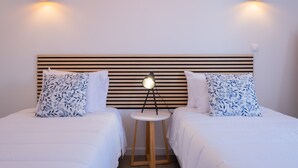 A hotel room with two beds, a round side table, and a modern headboard. - Vila da Pesca House (Rabo de Peixe)