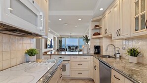 A modern kitchen with a large island, built-in appliances, and a view to the outdoors. - Oceanfront Kihei condo w/ sunset views and pool (Kihei)
