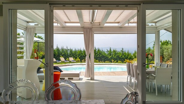 Zona piscina con vista su una catena montuosa, patio coperto e mobili da esterno.