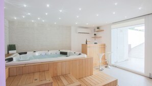 Una moderna spa con vasca idromassaggio, pavimento in legno e un'ampia porta scorrevole in vetro che dà sull'esterno.
