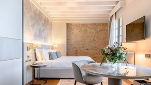 Une chambre moderne avec un grand lit, une table ronde et un mur en pierre.