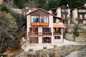 Ein Gebäude aus Stein mit einem Balkon, großen Fenstern und einer Steinmauer.