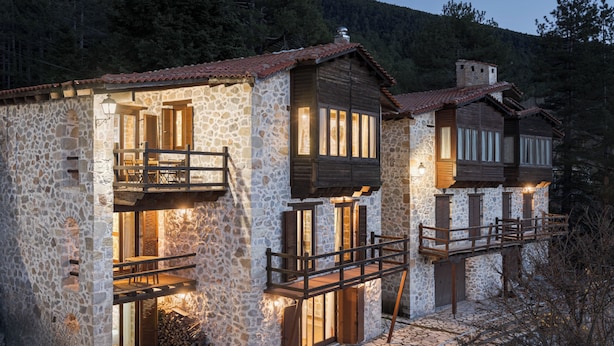 A stone building with wooden balconies and a stone staircase leading to a wooden deck. - Parnassus Woodstone Chalets- N1- N2- N3 (Delphi)