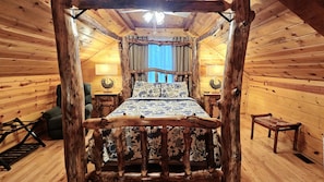 A rustic wooden room with a bed centered under a wooden canopy, flanked by two nightstands and a chair. - Green Heron in Hocking Hills (Logan)