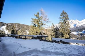 Ett snötäckt berglandskap med ett trästaket och snöbelagd mark.