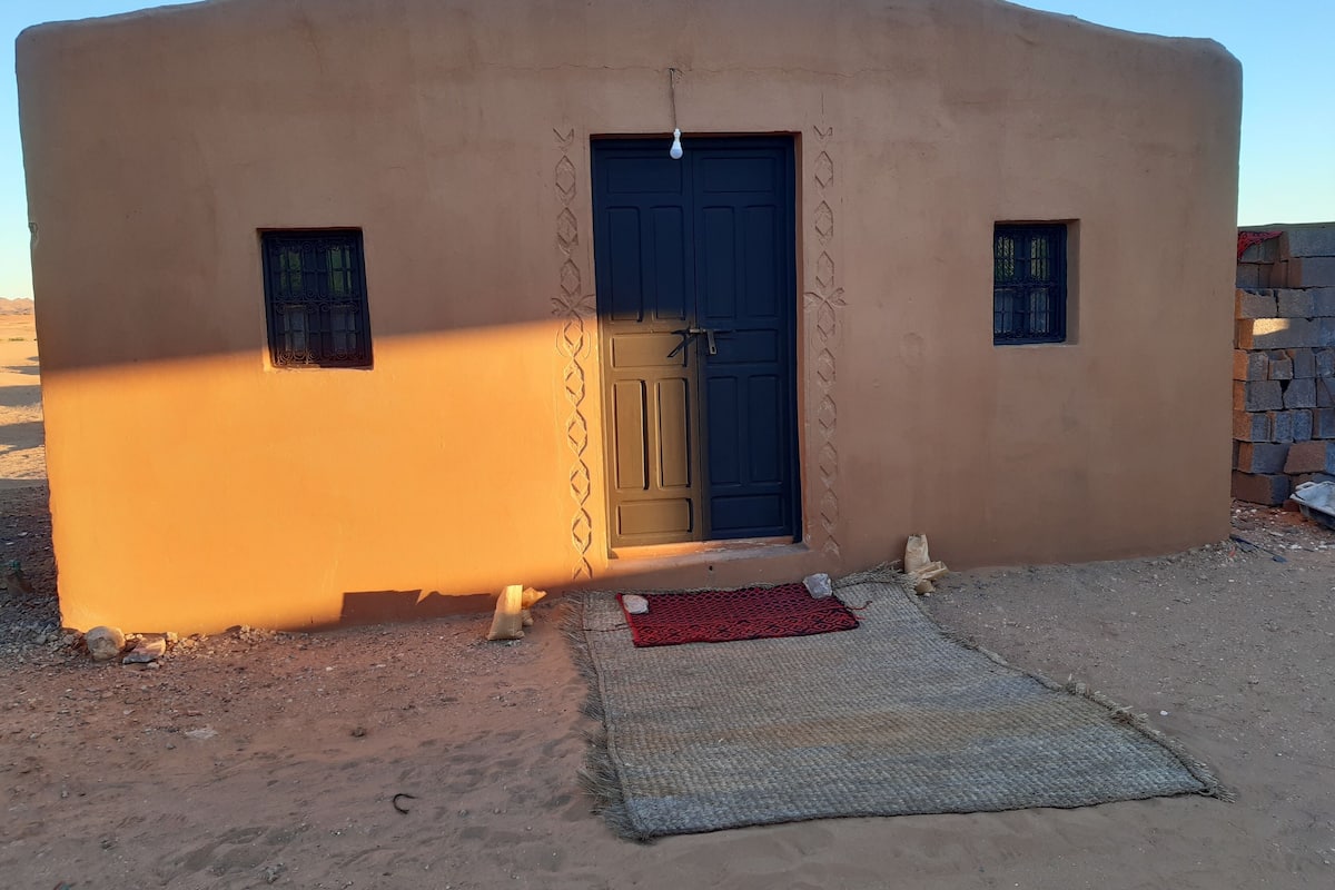 Un petit bâtiment d’un seul étage, doté d’un toit plat, d’une porte centrale et de deux petites fenêtres.