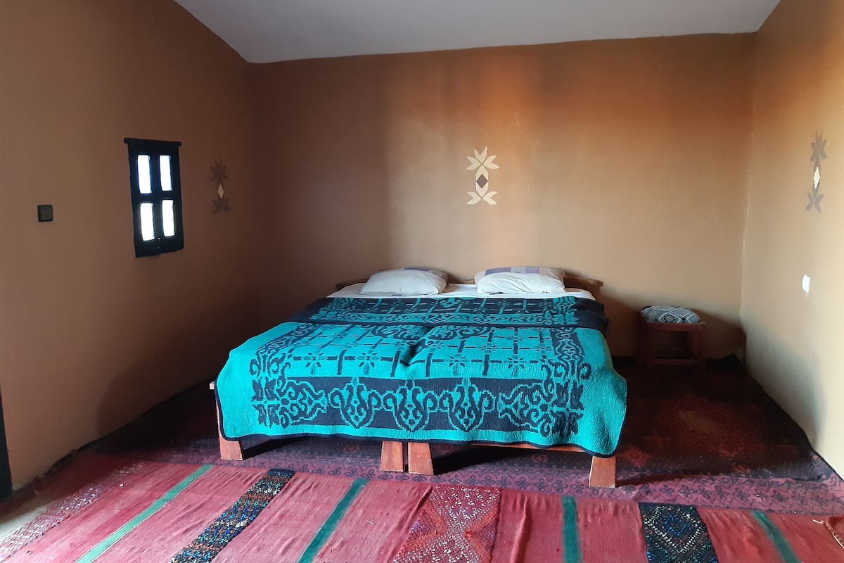 Une chambre à coucher avec un lit, une fenêtre et un élément décoratif mural.