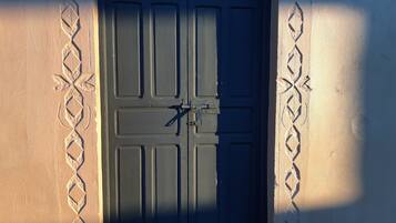 A closed dark wooden door with a metal latch, set in a wall with decorative patterns.