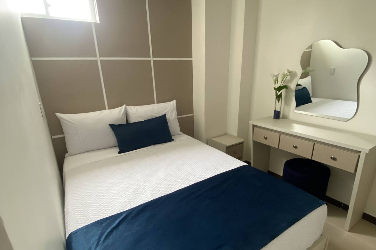 Un dormitorio moderno con una cama, un aparador y un espejo.