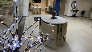 Un interior moderno con zona de comedor, un televisor montado en la pared y un espejo decorativo.