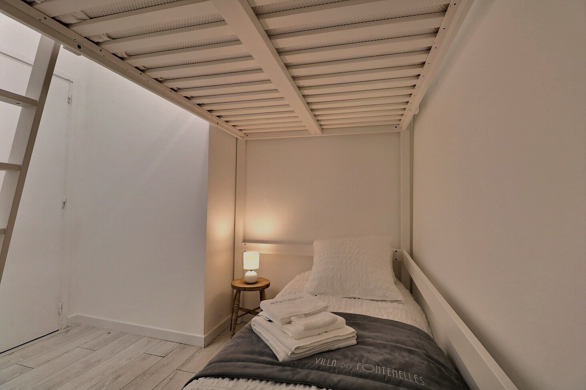 A bedroom with a bed, a bedside table with a lamp, and a door.