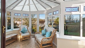 A conservatory with wicker furniture and stained glass windows. - Four Oaks - Sea and Harbour Views (Saundersfoot)