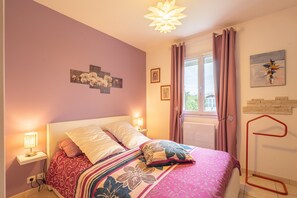 Un dormitorio con cama, lámparas de noche, una ventana con cortinas y decoración en la pared.