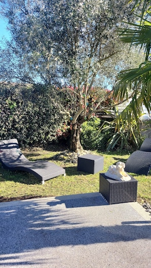 Outdoor seating with a tree and shrubs in the background. - Room in a Local Home Near Royan (SAUJON)