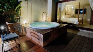 Eine Holztonne mit Whirlpool, einem Stuhl und einem Bett mit Vorhängen.