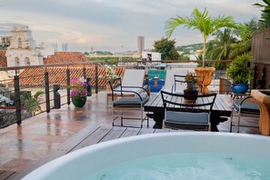 Une terrasse sur le toit équipée d’un jacuzzi, d’un espace salon et de plantes en pot.
